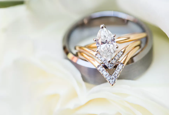 Diamond engagement ring sitting atop a silver wedding band.