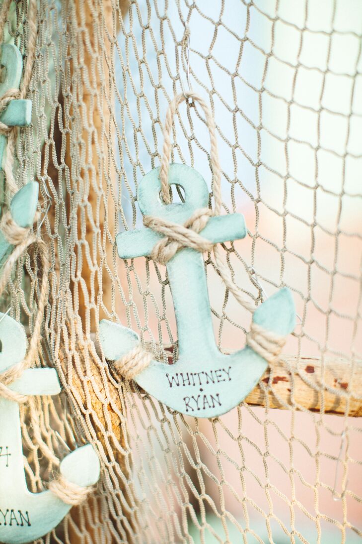 Whitney and her mother made the escort cards in themselves in the shape of small anchors — a perfect fit for the beach-inspired theme. They painted the painted wooden anchors with sea green-colored paint, wrapped them with jute and wrote guests’ names and table numbers on each. “We hung them on a ladder with fish net to display,” says Whitney. “They also double as a little memento from the wedding and can be used as a Christmas ornament.”rn