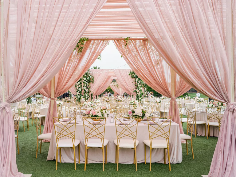 Pink draping provides a romantic aesthetic to this outdoor reception space.