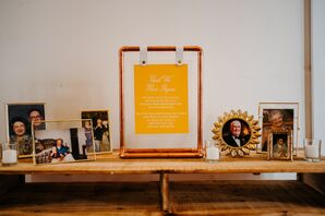 Memorial Table of Passed Loved Ones With Bright Yellow, Wes Anderson-Inspired Sign