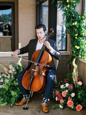 A Cellist Surrounded By Flower Arrangements Playing at Italian-Themed Rehearsal Dinner