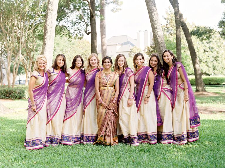 Bride and bridesmaids wearing purple, green, and gold saris. 
