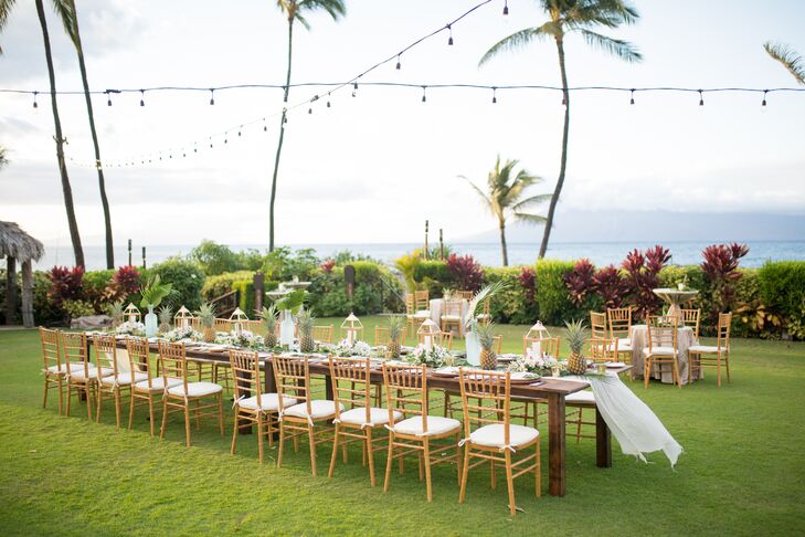 Bethany and Leonard hosted 20 guests at their outdoor reception at the Four Seasons Resort Maui in Wailea, Hawaii. A long banquet table was set with pineapples and banana leaves calligraphed in gold with the night's menu.
