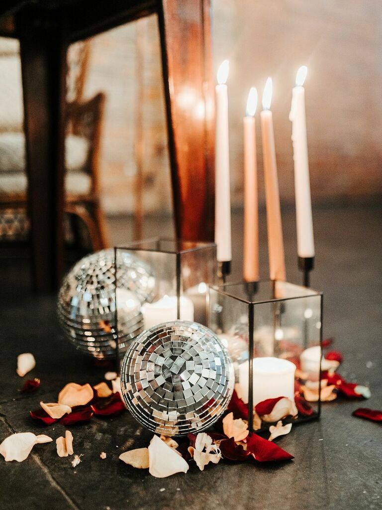 wedding decor with mini disco balls, white candles in square glass vases and red rose petals