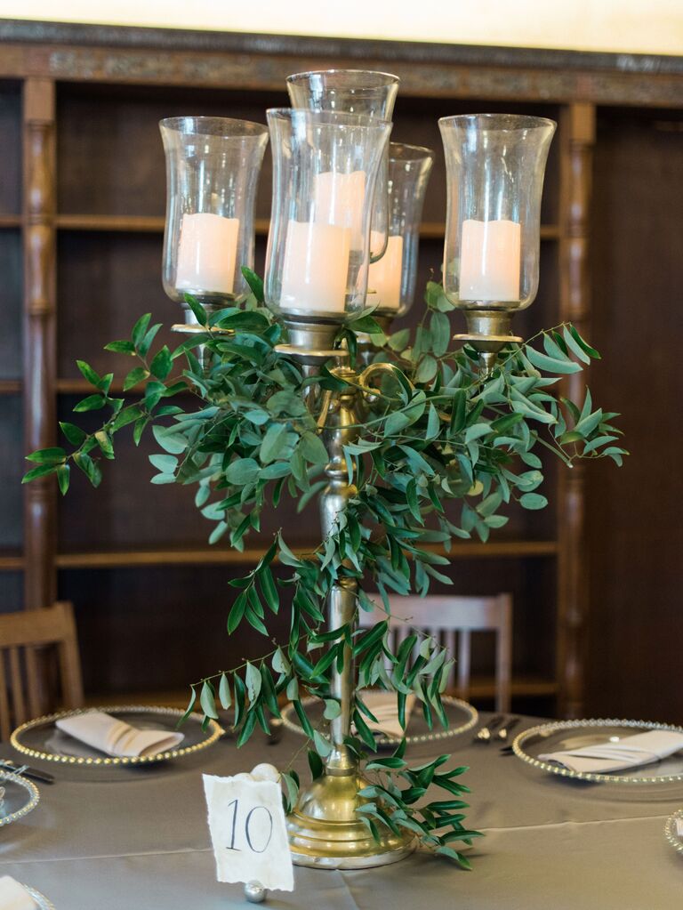 wedding centerpiece with gold candelabra decorated in greenery vines