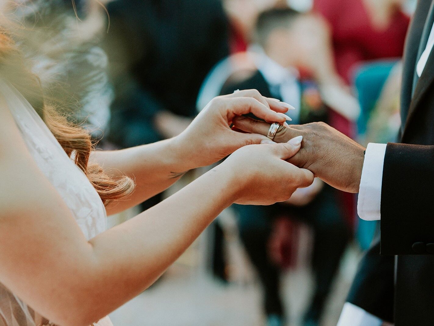A bride places a wedding band on her new husband's finger.