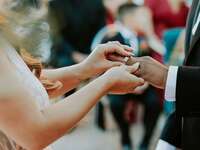 A bride places a wedding band on her new husband's finger.