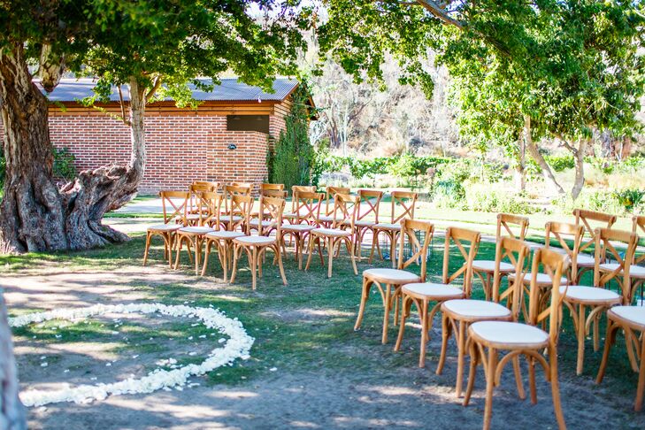 For Taylor and Cody’s relaxed outdoor ceremony, cross-back chairs were arranged in a semicircle and petals were sprinkled at the altar.