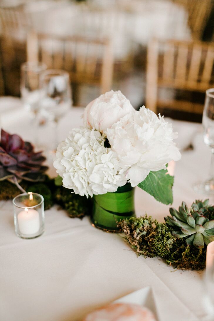 “I wanted the arrangements to feel like a piece of the outdoors was present,” Janel says. The couple kept this in mind and chose low, natural arrangements that wouldn’t obstruct their guests views. Cory Davenport, their florist, broke up each tablescape of succulents and moss with low white peony, white hydrangea and blush peony arrangements. Greenery wrapped around each cylinder vase, tying it to the natural tablescapes.