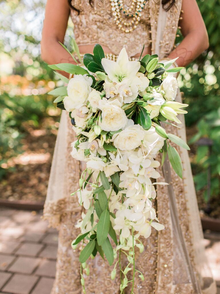 all white cascading wedding bouquet with lilies, roses, orchids and greenery