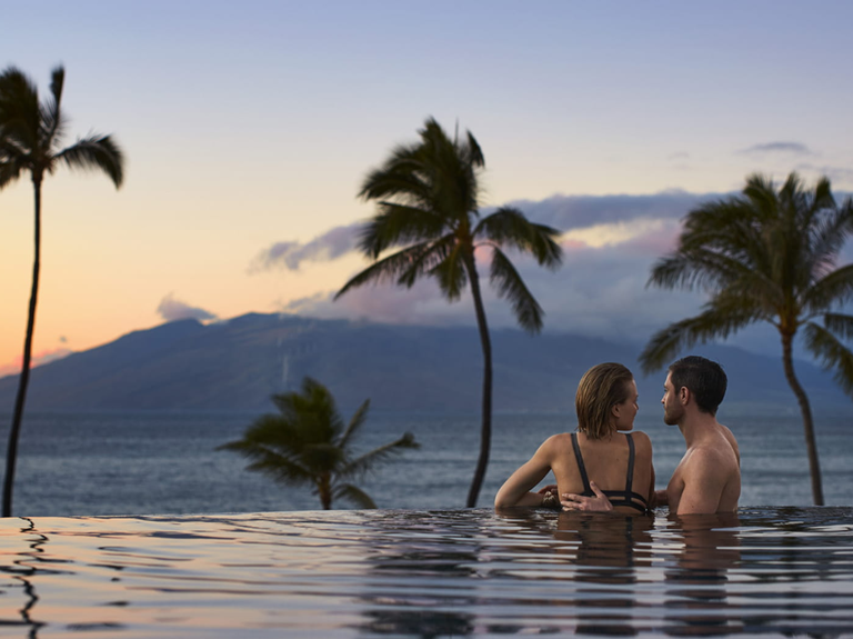 A couple enjoy the sunset at Four Seasons Resort in Hawaii.