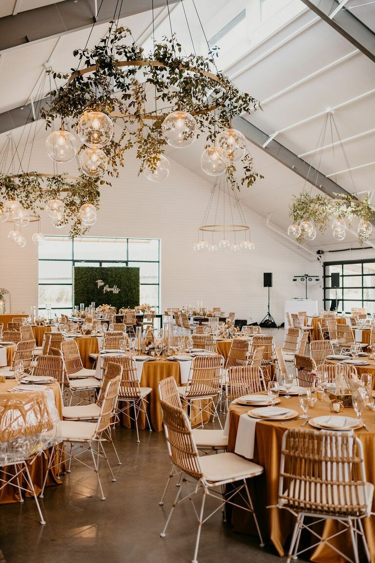 Boho wedding reception with greenery-covered chandeliers and leather chairs