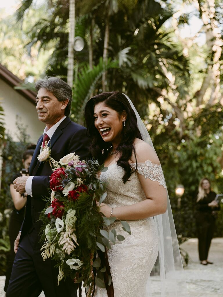 Bride walking down the aisle with father at tropical wedding ceremony