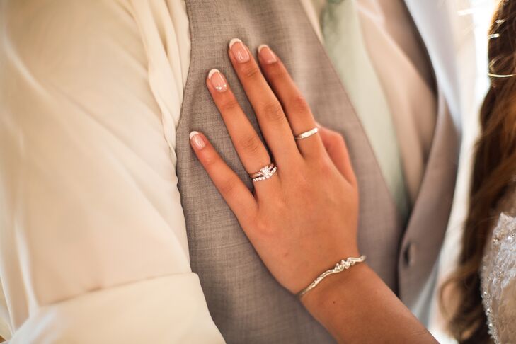 Denise rested her hand on James's gray vest, with beautifully manicured nails done for the wedding day. She wore a beautiful silver bracelet that complemented the collection of her elegant wedding rings.