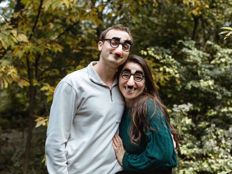 Couple poses for the camera wearing novelty disguises. 