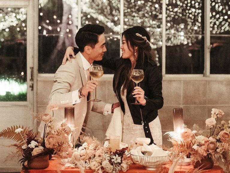 Groom with bride wearing leather jacket toasting during wedding reception
