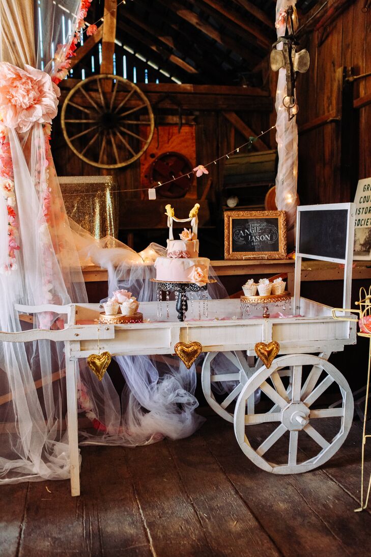 For dessert, Angie and Jason served an array of cupcakes and a blush wedding cake. They displayed the sweets on a white wagon cart decorated with gold hearts for a rustic, shabby-chic look.