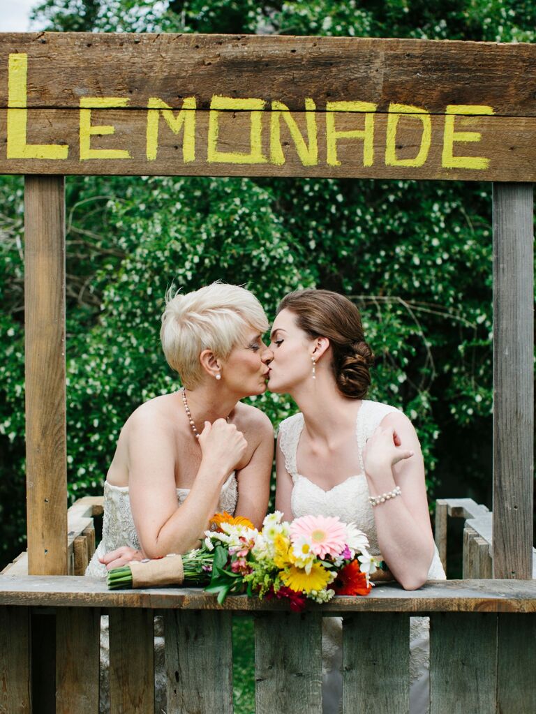 Couple shares a sweet kiss at a lemonade stand photo booth prop. 