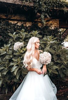 Bride in lace bodice wedding dress standing in front of hydrangeas