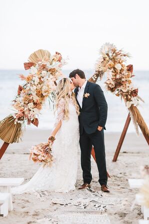 The Bride and Groom Share a Kiss in Front of the Wedding Arch