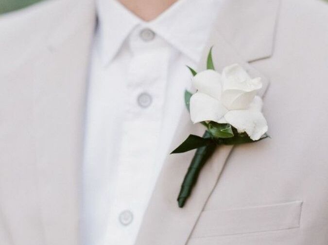 A gardenia boutonniere on the lapel of a neutral-toned suit