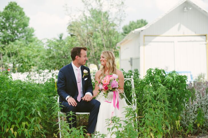 Brian sat with Lauren on a garden bench surrounded by lush greenery, wearing a light pink tie that matched the pops of pink seen within Lauren's bridal bouquet.