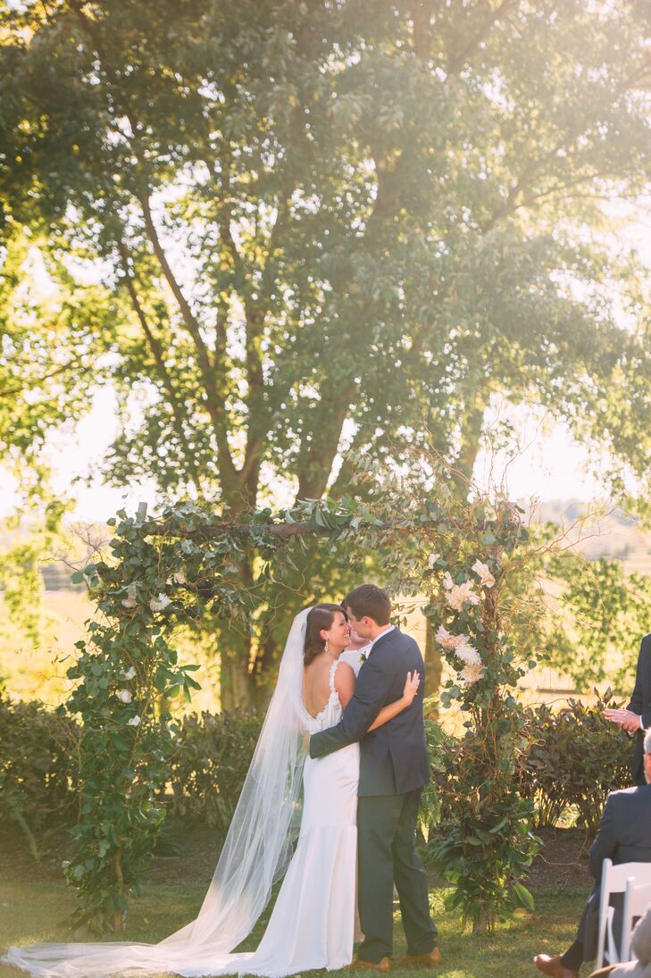 Molly and Ryan were married under a wooden wedding arbor that was decorated with greens and ivory dinner plate dahlias.