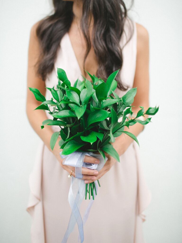 A bridesmaid holds a bouquet of vibrant greenery.