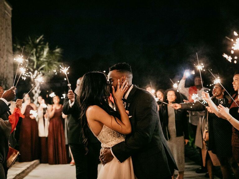 Bride and groom kissing under sparkler exit at summer wedding reception