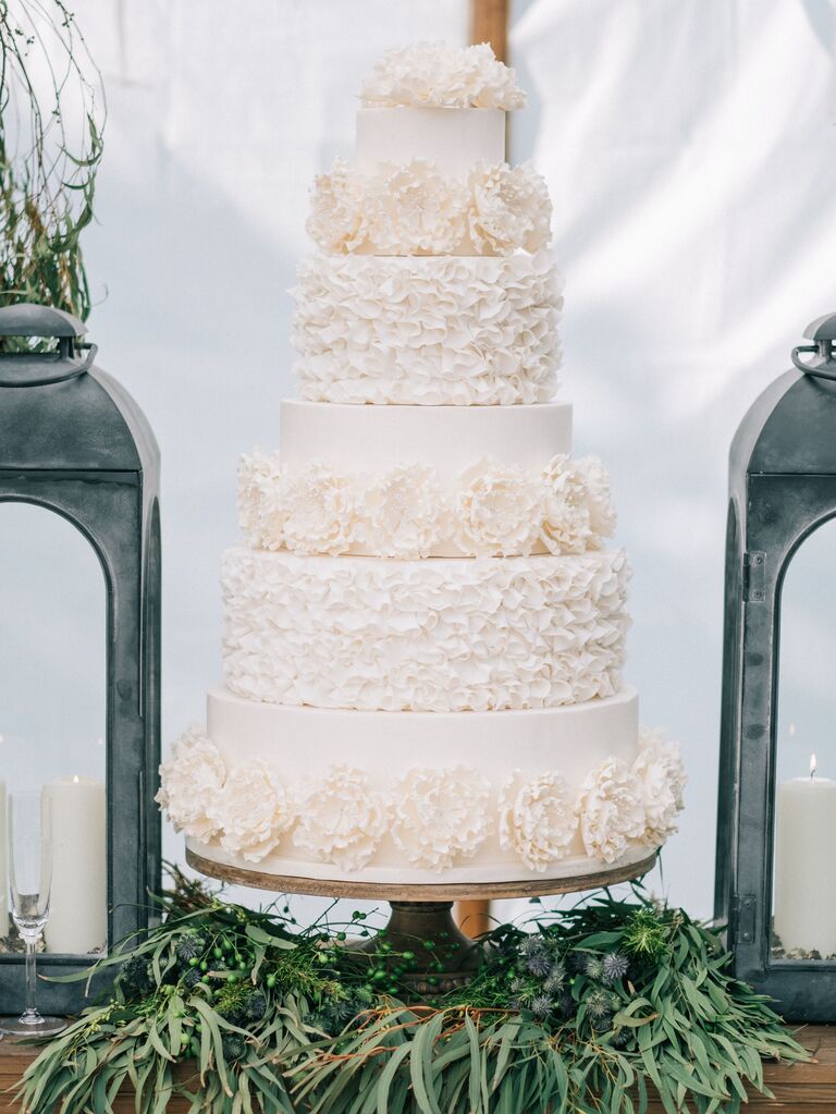white five tier wedding cake decorated with ruffled piping and sugar flowers