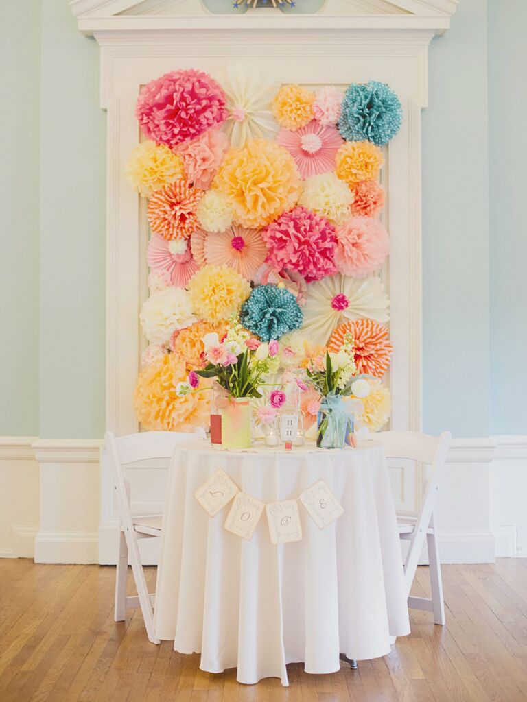 A bright paper flower backdrop behind the sweetheart table.