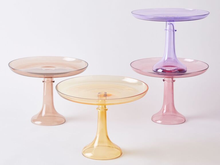 Four glass wedding cake pedestals in different pastel shades