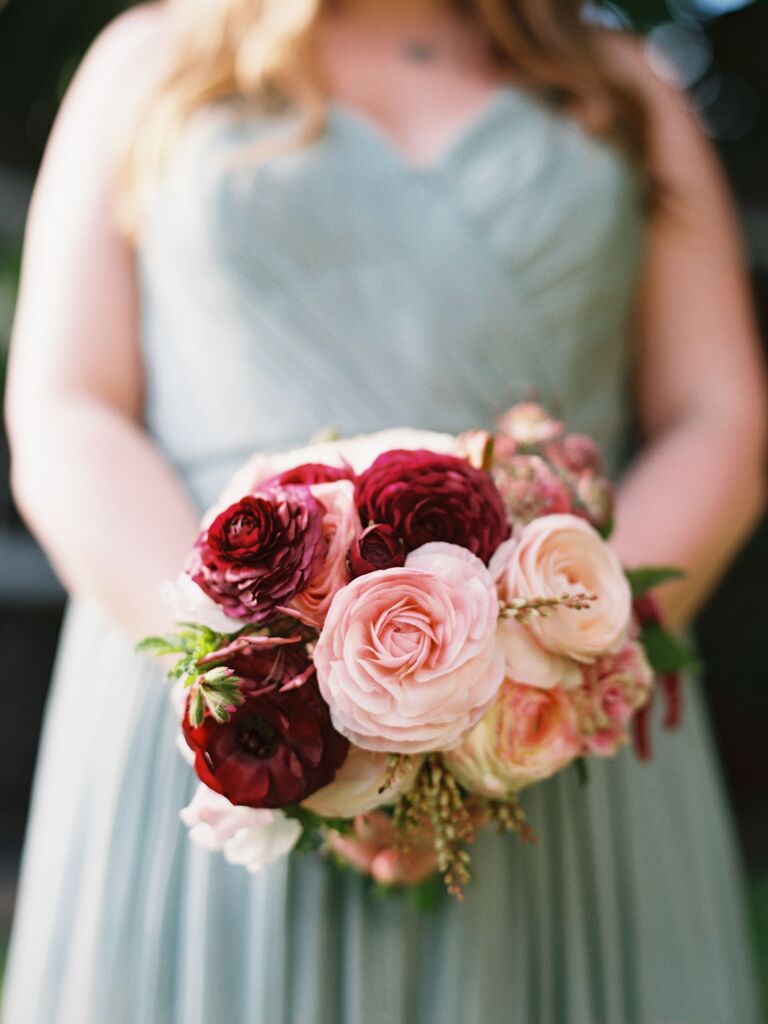 A bridesmaid holds this wine and peach-toned bouquet.
