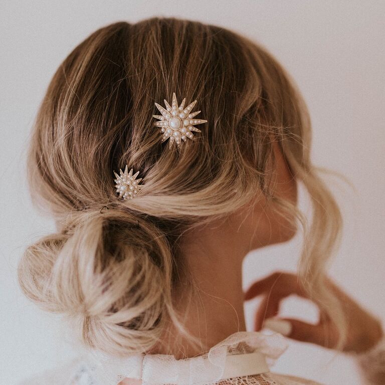 Model wears star-shaped pins embellished with pearls in her hair. 
