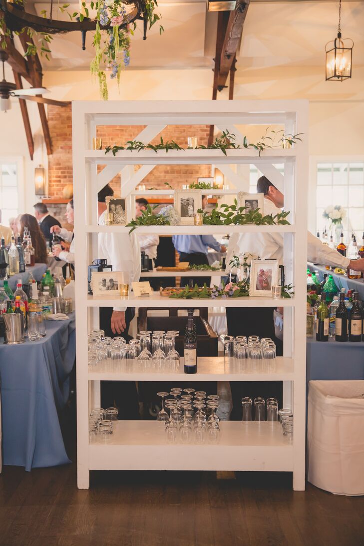 By the bar at the reception, a white bookcase featured photos of Jenna and Joshua and greenery on its shelves.