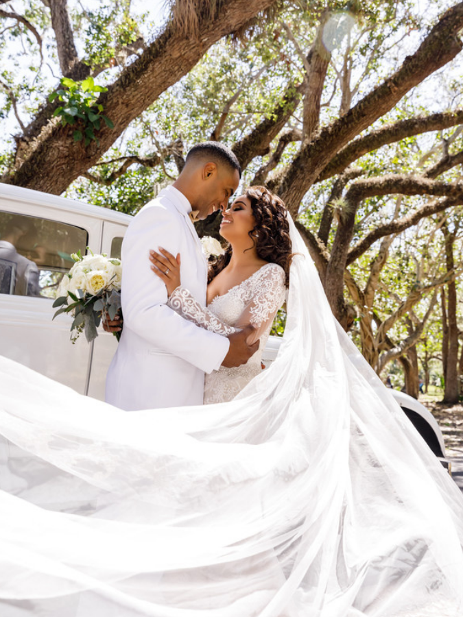 Couple sharing hug while wrapped in wedding veil