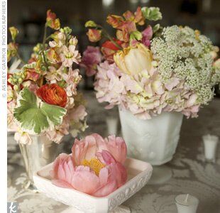Milk-glass vases, which the bride found on eBay, held ranunculus, Queen Anne’s lace, tulips, peonies, stock and hydrangeas. Underneath, damask linens added an antique vibe.