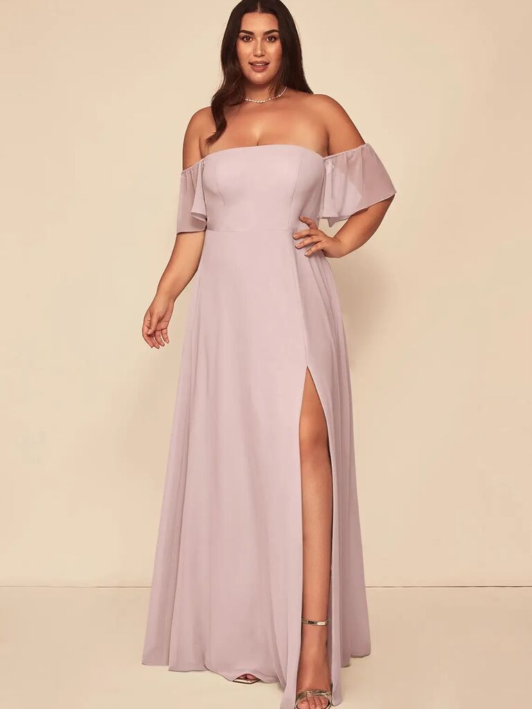 Model wears a lavender-colored gown with off-the-shoulder fluttering sleeves. 