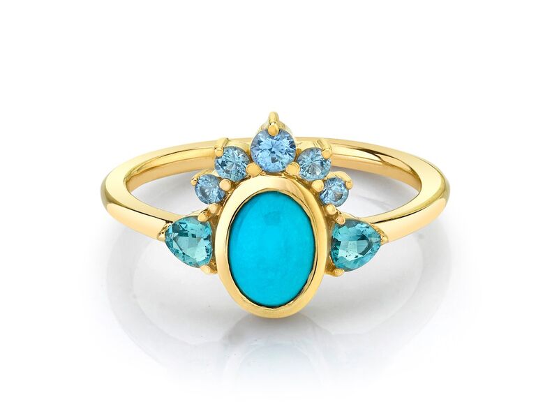 Gold ring with oval turquoise gem in center bordered by sapphires