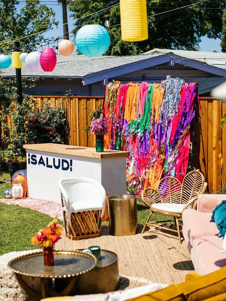 Colorful paper streamers bar space with "¡Salud!" sign.