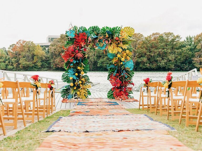 square wedding arch decorated with spray-painted monstera leaves in yellow, red and turquoise