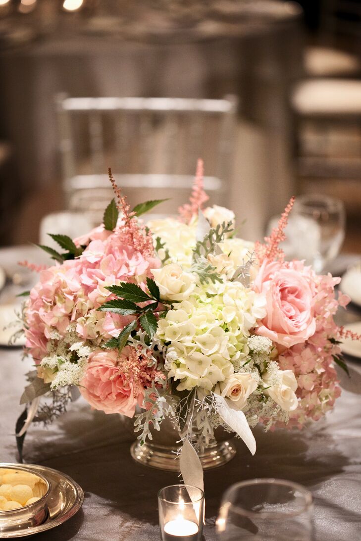 Pink and white roses, astilbe, stock and hydrangeas were displayed in low silver urns at the reception.