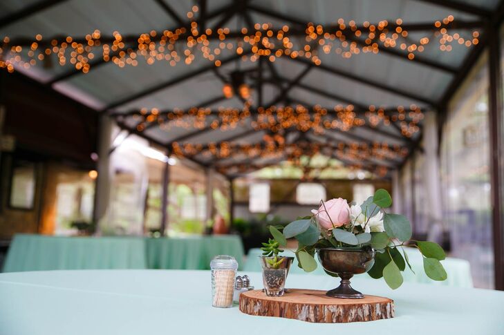 Mindy and her matron of honor designed all the wedding’s flower arrangements, ordering the blooms from FiftyFlowers.com. “My favorite flower is the king protea, so that was the focus,” Mindy says. “Along with proteas, we had succulents, pink cabbage roses, white dahlia-style cremons and silver dollar eucalyptus.” The flowers were artfully arranged in vintage, tarnished silver vases and a variety of glass vessels atop tree-trunk slices and alongside petite potted succulents.