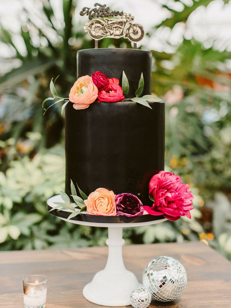 Small two-tier black wedding cake with pink and orange flowers and custom motorcycle cake topper