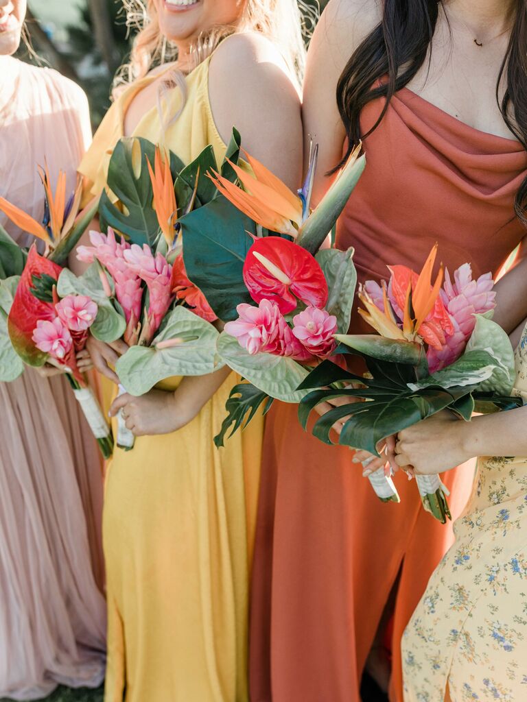 Bridesmaids hold vibrant tropical flower bouquets.