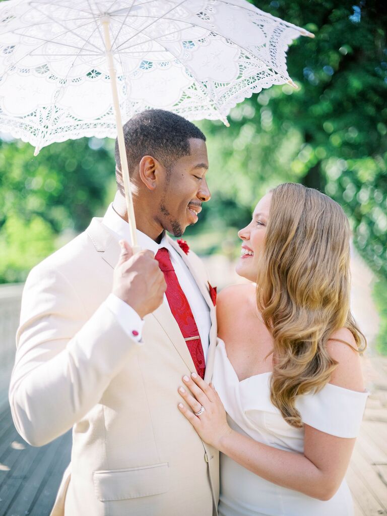 bride and groom stand under white cloth parasol