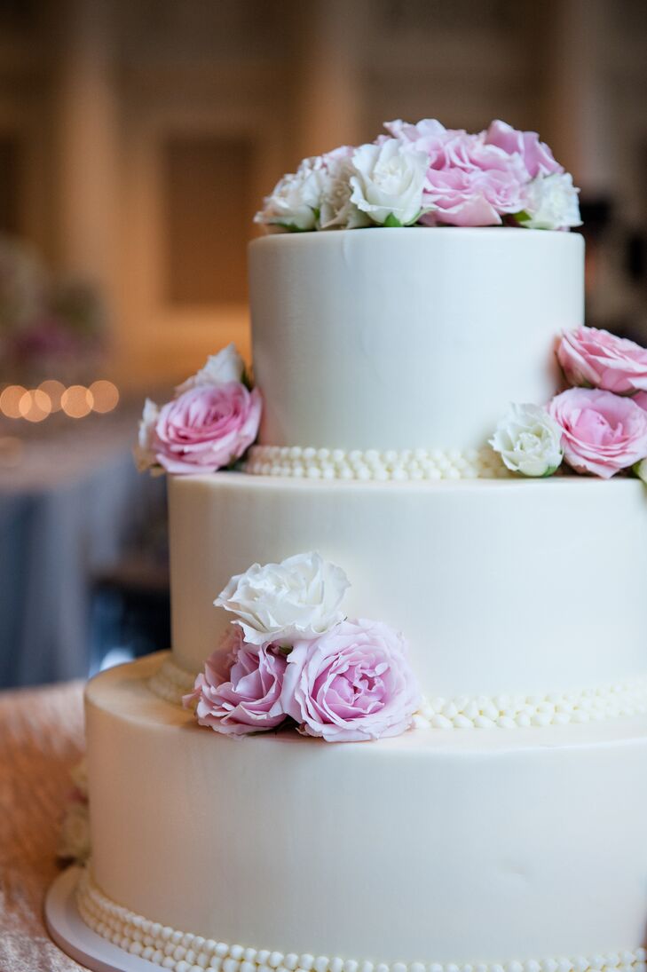 The couple's three-tiered wedding cake was classic white, topped with pink and white roses that matched the color palette of the rest of the wedding decor.