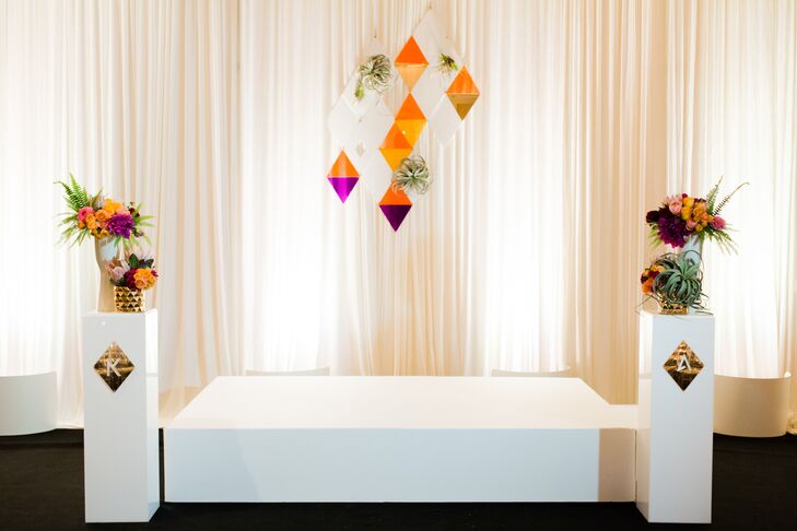 Kelly and Adam brought in white draping and black carpeting, transforming the ballroom space for the ceremony. Custom laser cut shapes provided a colorful and unique backdrop for their I do's.