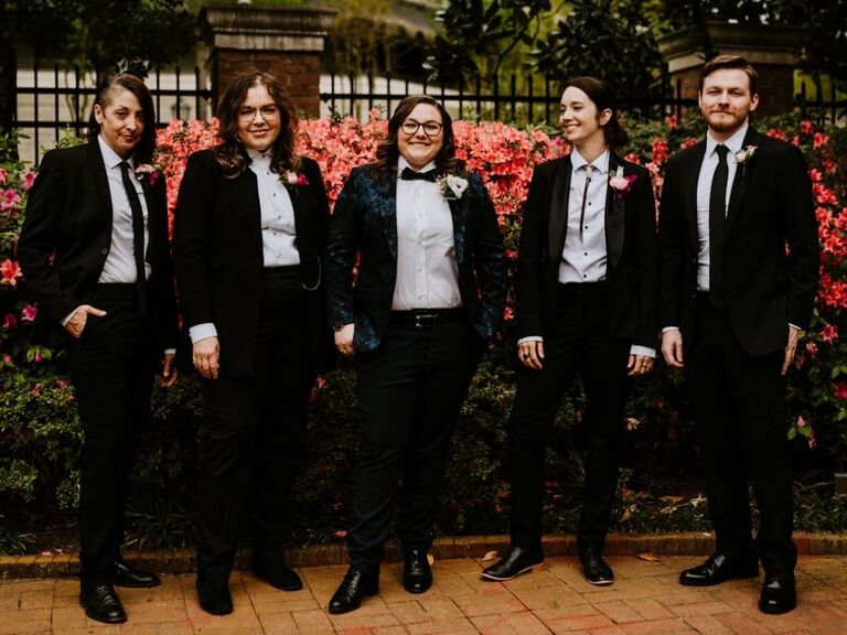 bride posing with wedding party members in suits