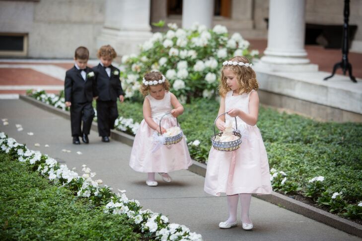 The couple's two flower girls wore light pink and ivory satin dresses by US Angels. The girls carried baskets of pink rose petals which they scattered across the ceremony aisle.